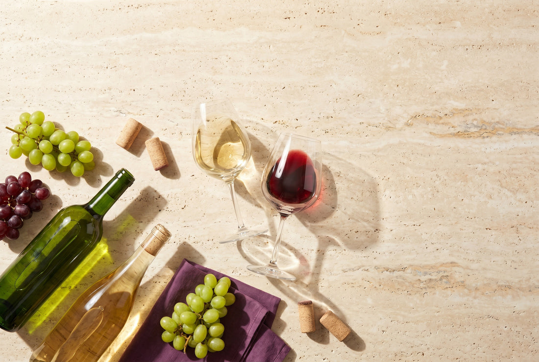Alkoholfreier Wein in zwei Gläsern mit Trauben und Korken auf Travertin