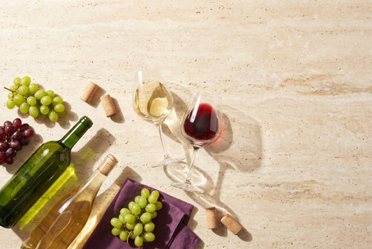 Alkoholfreier Wein in zwei Gläsern mit Trauben und Korken auf Travertin