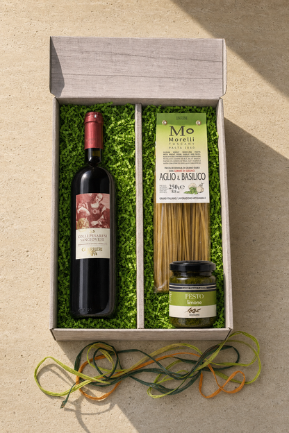 Italienisches Genuss-Präsent — Sangiovese, Linguine & Pesto Limone im offenen 2er-Karton, Top-Down Editorial auf Travertin mit warmem Sonnenlicht von oben rechts